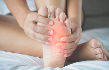 woman holding top of the foot feeling pain