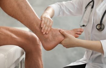 Sports injury. Doctor examining patient's foot in hospital, closeup